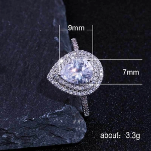 Elegant pear-shaped zircon ring with double halo setting on dark stone background