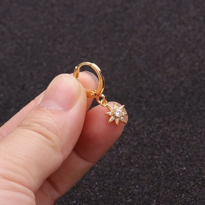 Close-up of a gold star charm hoop earring with a sparkling zircon inlay on fingers