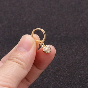 Close-up of a gold huggie earring with a shimmering micro-pave heart shaped pendant