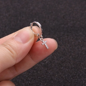 Close-up of silver hoop earring with micro-paved zircon cross pendant detail