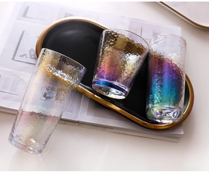 Close-up of three colorful hammered glass cups on a black and gold tray in a home setting
