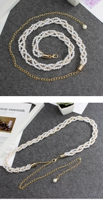 Detail view of multi-layer pearl waist chain with golden alloy clasp on grey background