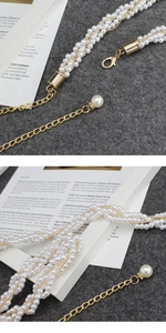 Detailed macro view of white pearl bead chain with gold lobster clasp and extension link