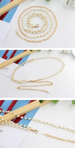 Detail of elegant gold metal waist chain with white pearls and lobster clasp closure