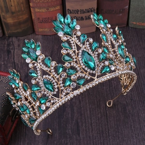Close-up of golden bridal crown with emerald green teardrop gems and sparkling crystals