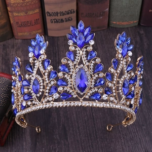 Detailed view of a golden crown with navy blue teardrop gems and floral crystal accents
