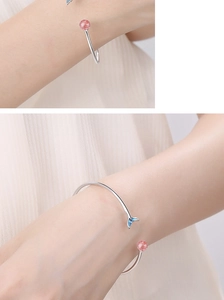 Close-up of silver fish tail bracelet with pink strawberry quartz and blue gradient charm