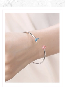 Detail of adjustable silver bangle with blue mermaid tail and strawberry quartz bead