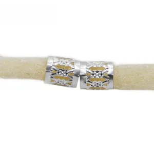 Macro shot of silver hollowed-out embossed metal rings on braids hair extensions