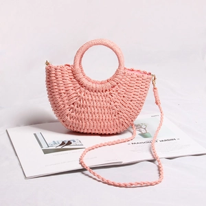 Detailed view of pink straw woven half-moon handbag with round handle on stylish background