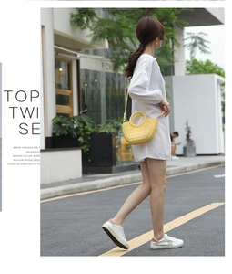 Outdoor shot of a bright yellow semi-circular straw bag styled with a white dress