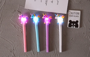 Dettaglio di quattro penne unicorno luminose in rosa, blu, viola e bianco su una scrivania