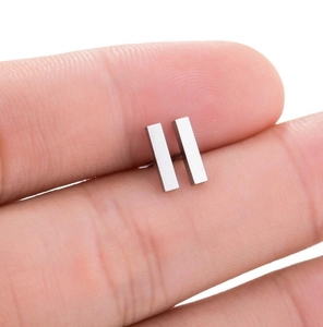 Macro detail of minimalist silver geometric stud earrings held between fingertips