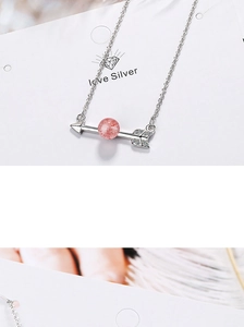 Macro shot of silver arrow pendant with pink stone and white crystals on card