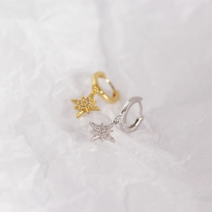 Macro shot of silver and gold star drop hoop earrings with sparkling crystal accents