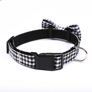 Close-up of black and white gingham pet collar with detachable bow and metal D-ring
