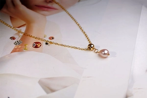 Detailed view of teardrop pink pearl pendant on a gold titanium steel chain necklace