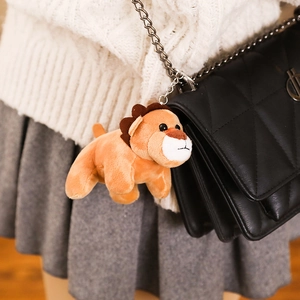 Cute lion plush keychain hanging on a black quilted bag with a silver chain link