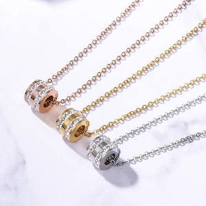 Detailed view of three cylindrical pendant necklaces in rose gold, gold, and silver finishes