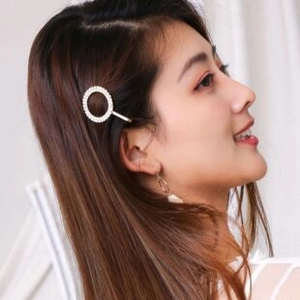 Detail showing elegant pearl circular hair clip and matching hoop earrings on model