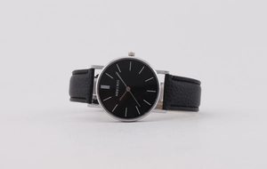 Close-up of a minimalist men's watch featuring a black dial and silver metal case