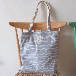 Detail of blue herringbone canvas tote bag hanging on a wooden chair with woven texture