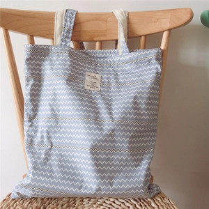 Close-up of blue zigzag canvas tote bag with woven shoulder straps on a chair