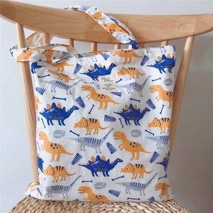 Detail of canvas tote bag with dinosaur patterns hanging on a minimal wooden chair