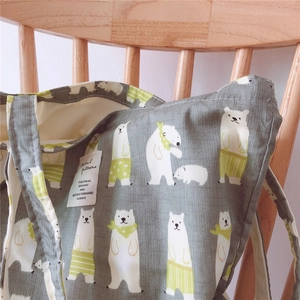 Detail of grey-green canvas tote bag with cartoon polar bear prints on wooden chair