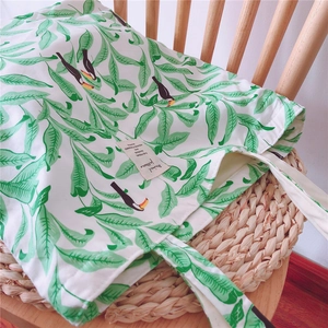 Detail of canvas tote bag with tropical leaf print and hornbill bird on a wooden chair