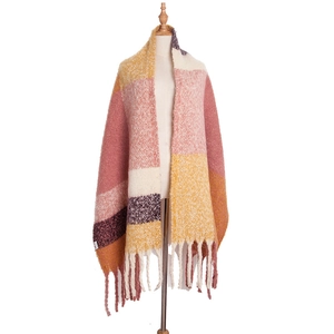 Detail of chunky knit scarf with multi-color blocks and long fringe tassels for winter