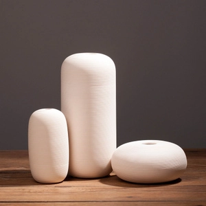 Three-piece modern white ceramic vase set with elegant spiral texture on wooden table