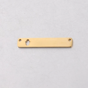 Detailed macro of gold plated rectangular pendant with palm cutout and dual hanging holes