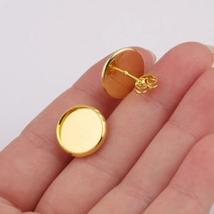 Polished 12mm gold plated stainless steel stud earring blanks held on a finger for scale