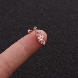 Macro view of rose gold star and zircon ear stud held on finger to show precise size