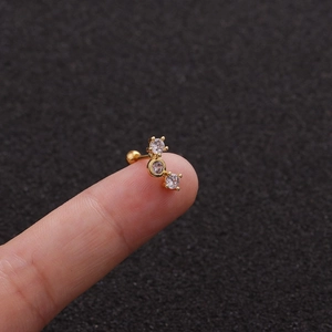 Macro detail of gold stainless steel stud featuring three vertical clear cubic zirconia