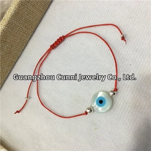 Detailed top view of natural shell evil eye bead on a red braided string bracelet
