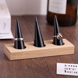 Bamboo and wood jewelry stand with three black cone ring holders and a solid rectangular base