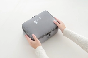 Detail of grey travel makeup bag with dual zippers and exquisite life slogan print