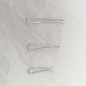 Three-piece set of curved U-shaped silver metal hair clips in various sizes on white fabric