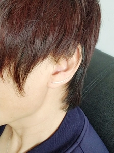 Side view of minimalist curved silver U-shaped clip-on earring worn on the earlobe