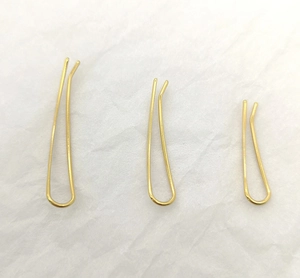 Three sizes of smooth gold curved U-shaped ear clips on a white textured backdrop