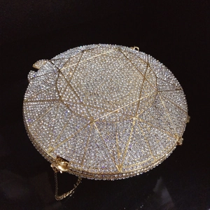 Detailed close-up of a circular evening bag with crystal rhinestones and gold metal clasp