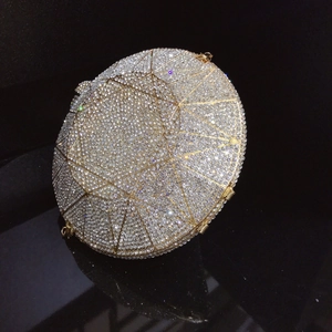 Close-up of diamond-shaped clutch bag with silver rhinestones and gold metal frame