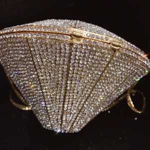 Close-up of luxury scallop evening bag with white crystals and gold metal frame