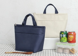 Detailed view of insulated lunch bags in navy and beige on a picnic-style table