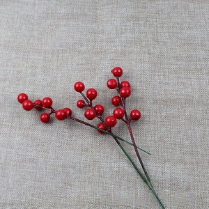 Detail view of 7-head red artificial berries on textured linen for Christmas decor