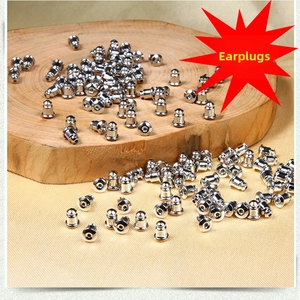 Pile of shiny silver stainless steel butterfly earring backs on a rustic wood slice