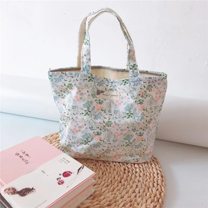 Close-up of floral cotton tote bag with zipper and logo label on woven mat backdrop