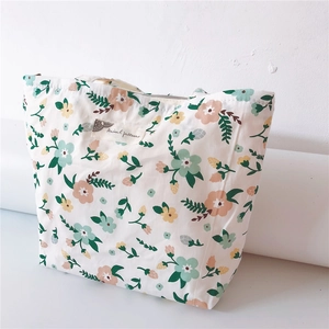 Detail of floral canvas tote bag featuring secure zipper closure and woven label logo